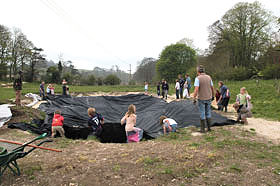 People placing a black butyl liner in a newly excavated pond